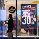 Αγορές σε κατάστημα με Black Friday ταμπέλες και εκπτώσεις.