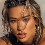 Cindy Prado με trench jacket, δερμάτινο σορτς και animal print clutch σε urban fashion εμφάνιση