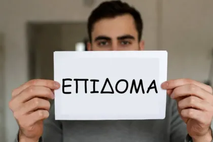 Άτομο κρατάει έγγραφο με πληροφορίες για το επίδομα των 250 ευρώ – πότε πληρώνεται, ποιοι το δικαιούνται και εισοδηματικά κριτήρια