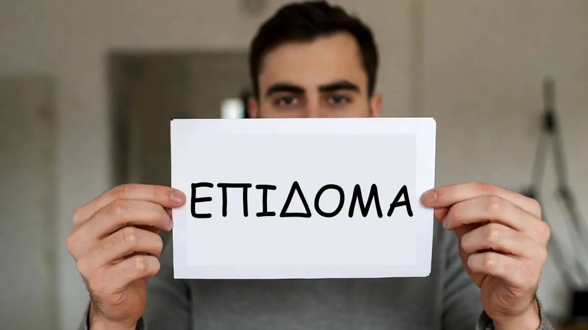 Άτομο κρατάει έγγραφο με πληροφορίες για το επίδομα των 250 ευρώ – πότε πληρώνεται, ποιοι το δικαιούνται και εισοδηματικά κριτήρια