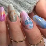 Close-up φωτογραφία με μανικιούρ σε marble σχέδιο σε λευκούς και χρυσούς τόνους.