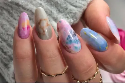 Close-up φωτογραφία με μανικιούρ σε marble σχέδιο σε λευκούς και χρυσούς τόνους.