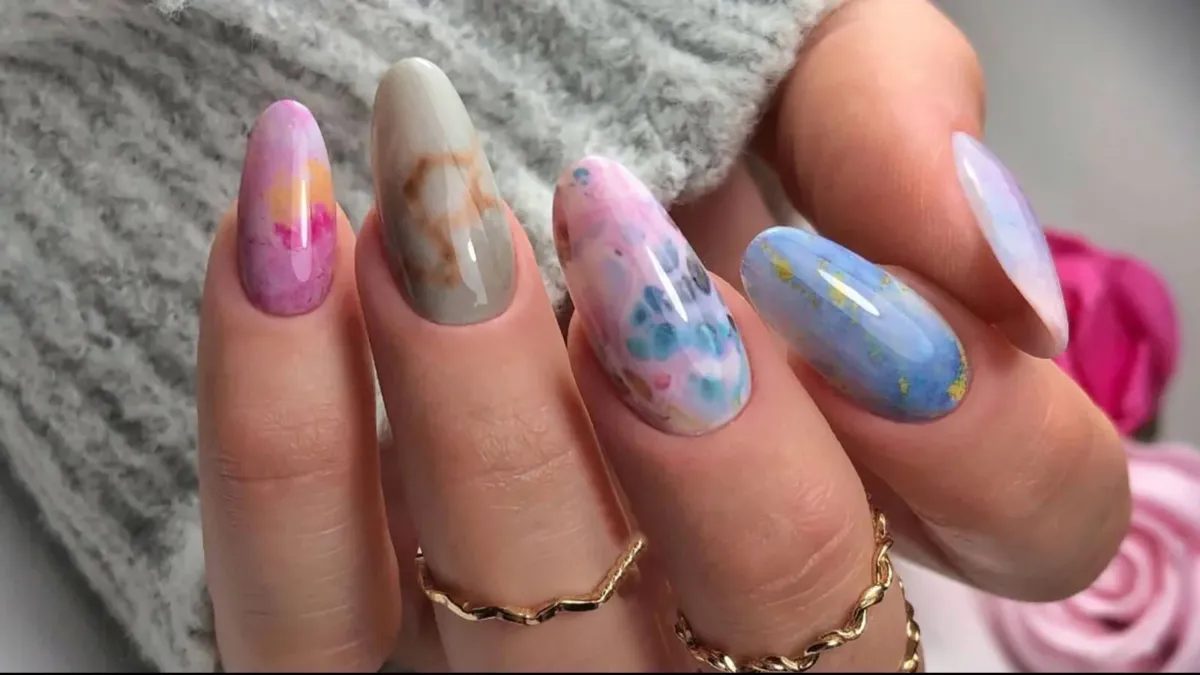 Close-up φωτογραφία με μανικιούρ σε marble σχέδιο σε λευκούς και χρυσούς τόνους.