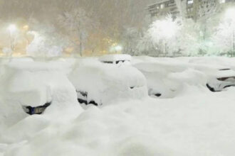 Χιονισμένο τοπίο σε ευρωπαϊκή πρωτεύουσα με ακινητοποιημένα οχήματα και πυκνή χιονόπτωση.