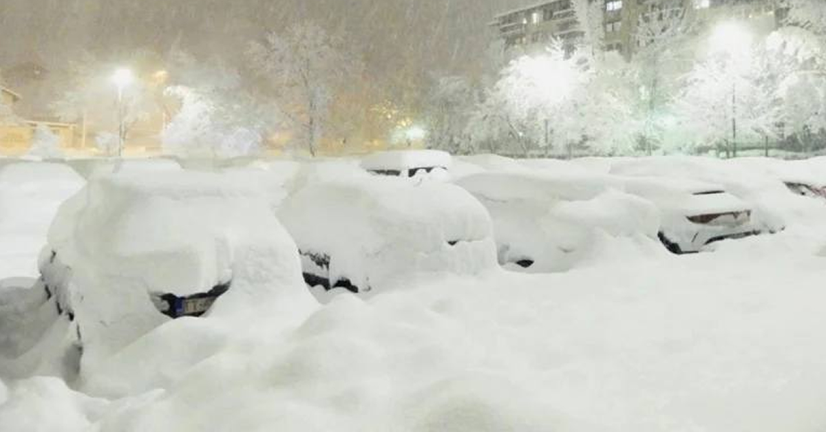 Χιονισμένο τοπίο σε ευρωπαϊκή πρωτεύουσα με ακινητοποιημένα οχήματα και πυκνή χιονόπτωση.