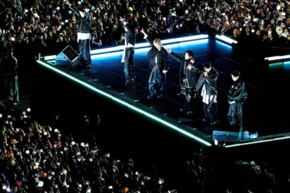 Τα μέλη του συγκροτήματος BTS τραγουδούν σε εξωτερική σκηνή στη Σεούλ μπροστά σε χιλιάδες οπαδούς με φώτα.