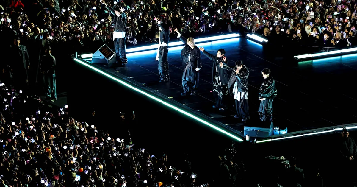 Τα μέλη του συγκροτήματος BTS τραγουδούν σε εξωτερική σκηνή στη Σεούλ μπροστά σε χιλιάδες οπαδούς με φώτα.
