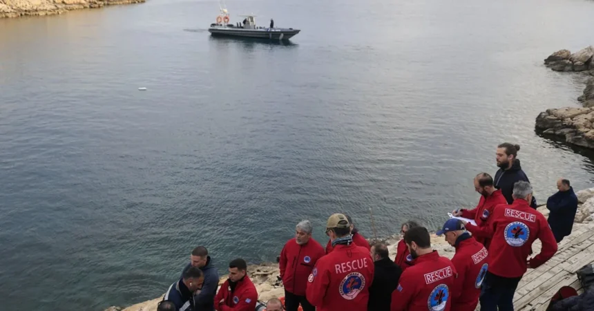 Άνδρες των σωστικών συνεργείων επιχειρούν σε βραχώδη ακτή με φόντο τη θάλασσα, γύρω από σωστικό εξοπλισμό.