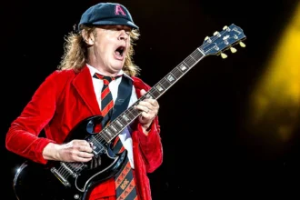 Stevie Young των AC/DC παίζει κιθάρα στη σκηνή φορώντας το χαρακτηριστικό του καπέλο και γιλέκο.