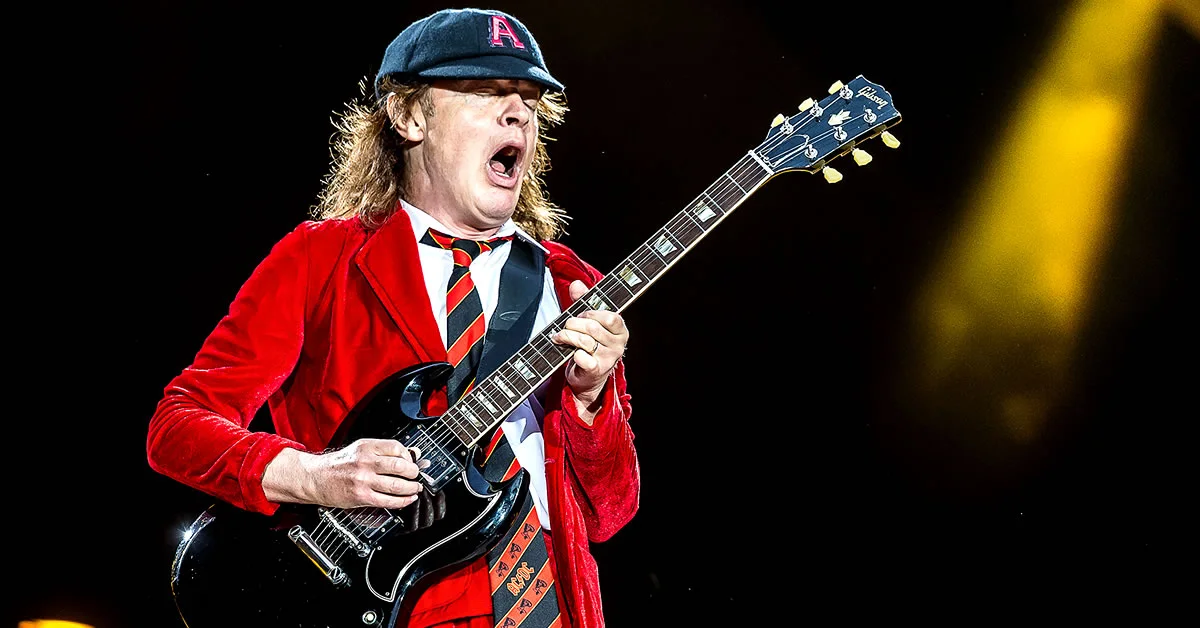 Stevie Young των AC/DC παίζει κιθάρα στη σκηνή φορώντας το χαρακτηριστικό του καπέλο και γιλέκο.
