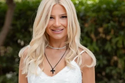 Η Φαίη Σκορδά ποζάρει λαμπερή, φορώντας ένα κομψό λευκό μίνι φόρεμα με λεπτομέρειες δαντέλας και εντυπωσιακά χρυσά ψηλοτάκουνα πέδιλα.