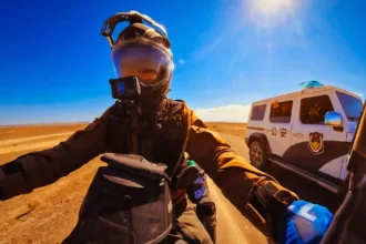 Μια γυναίκα πάνω σε μοτοσικλέτα μιλάει με Κινέζους αστυνομικούς στη μέση ενός έρημου δρόμου, στην επαρχία Ξινγκιάνγκ.