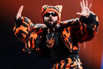Ο Akylas ποζάρει με χιούμορ μπροστά στο τρόπαιο της Eurovision 2026.
