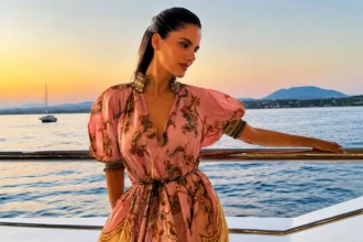 Η Αλεξάνδρα Νίκα φορά αέρινο καλοκαιρινό φόρεμα πάνω σε σκάφος με φόντο το ηλιοβασίλεμα στη θάλασσα.