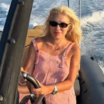 Ελένη Μενεγάκη χαμογελαστή στο τιμόνι φουσκωτού στις καλοκαιρινές διακοπές