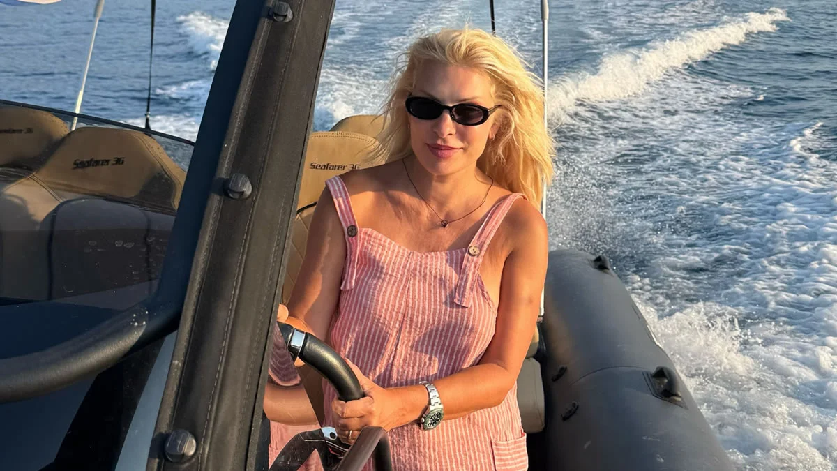 Ελένη Μενεγάκη χαμογελαστή στο τιμόνι φουσκωτού στις καλοκαιρινές διακοπές